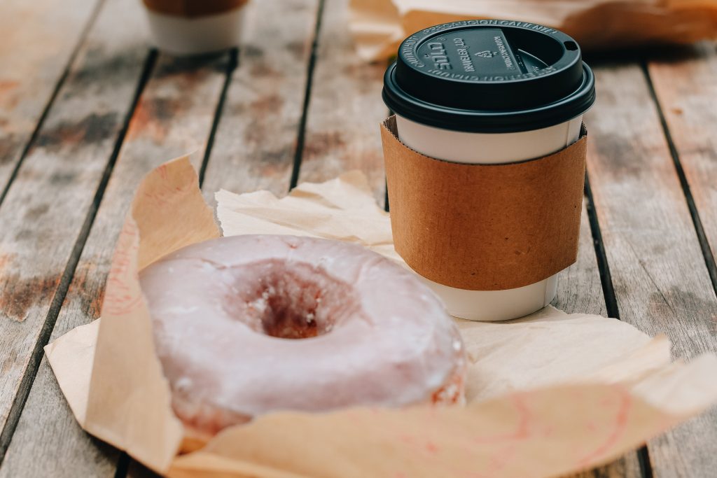 A picture of coffee and a donut. Photo credit Pexels.